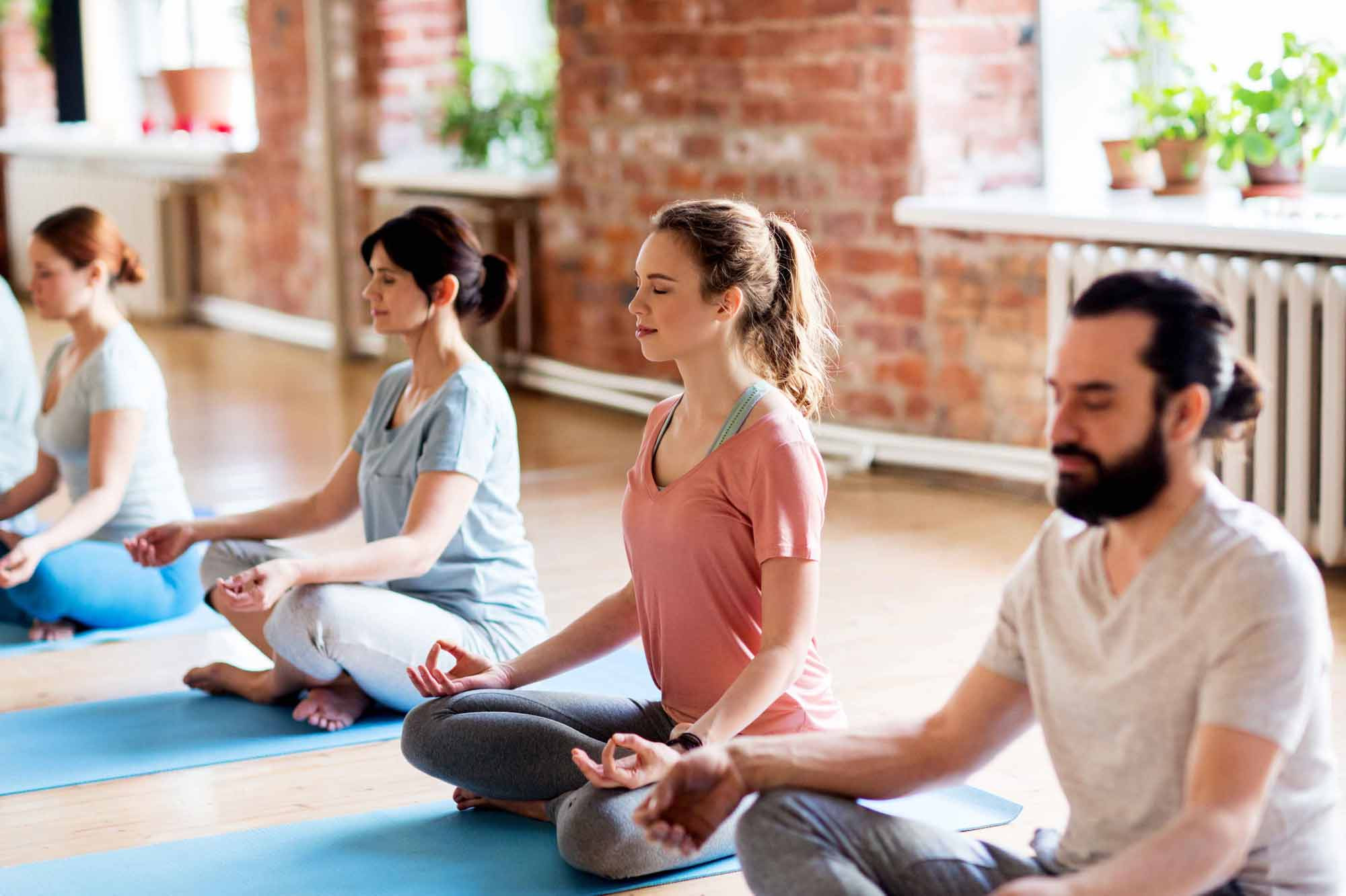 Gruppe von Menschen, die Yoga-Übungen im Studio machen
