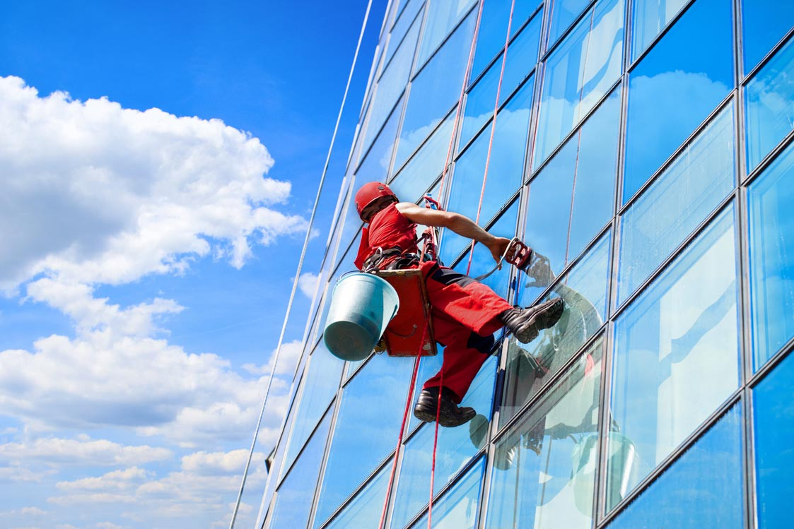 Gebäudereiniger bei der Arbeit an der Außenfassade eines Hochhauses