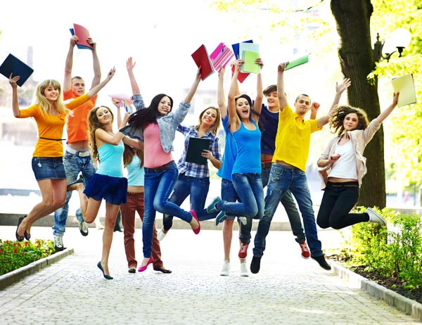 Fröhliche springende Teenager/ junge erwachse mit Blöcken in der Hand