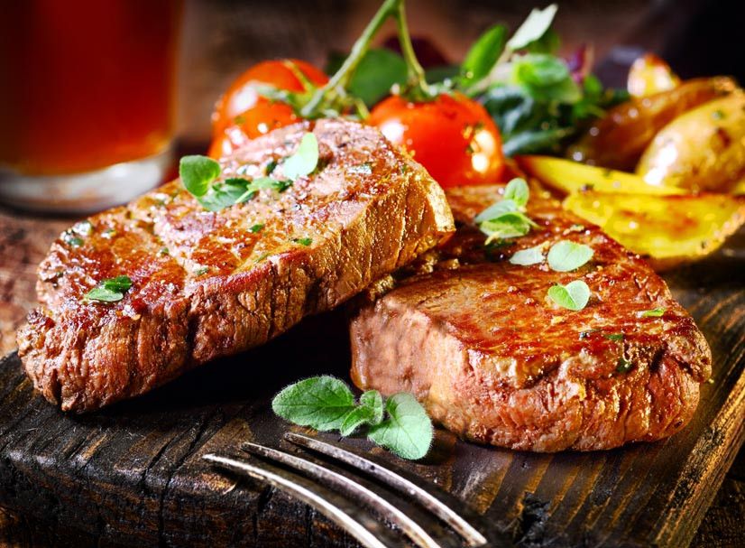 Vom Fleischer-Meister gebratene Steaks serviert mit Tomaten und Kartoffeln 