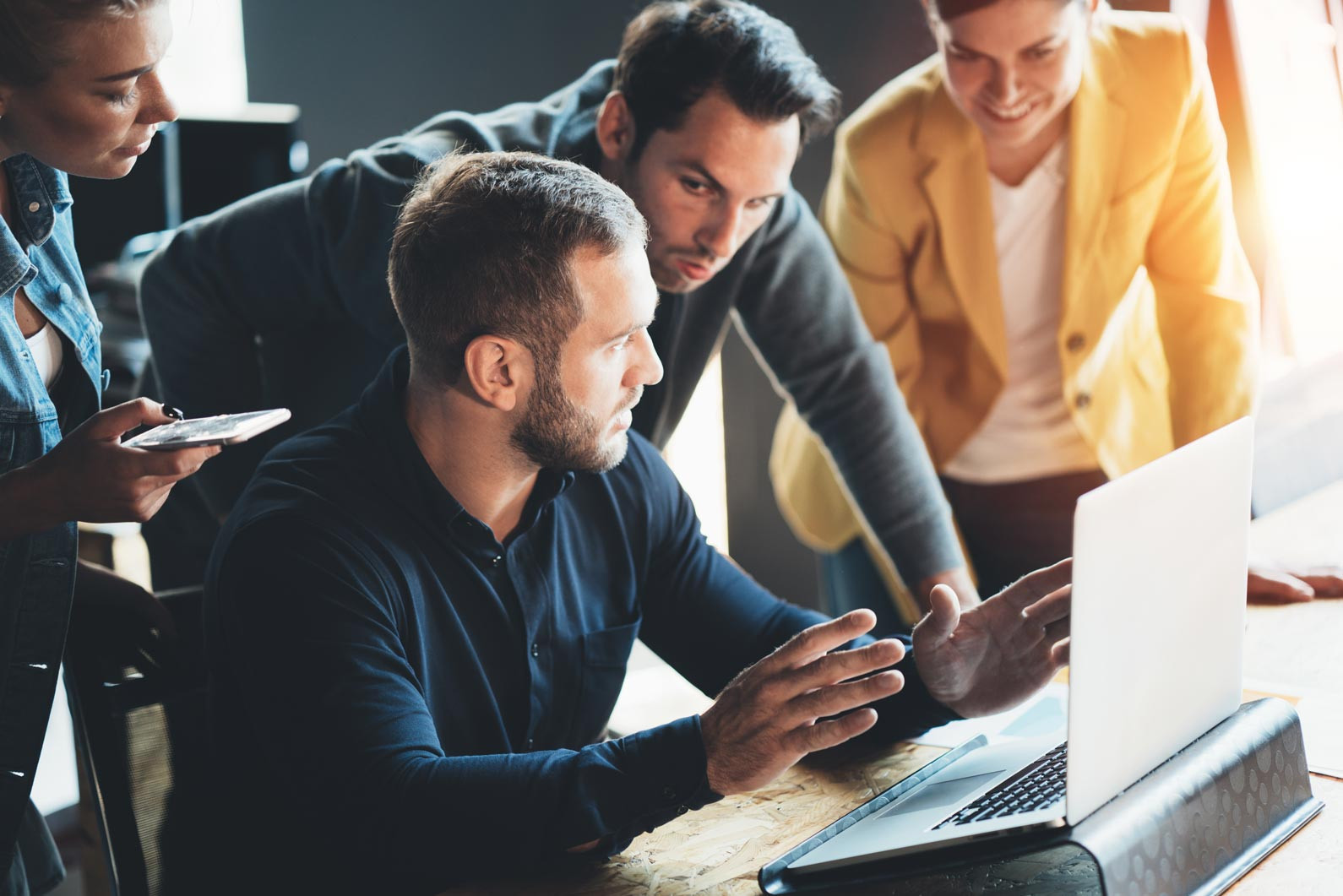 Mitarbeiter eines Ingenieurbüros bei der gemeinsamen Arbeit am Laptop und Smartphone