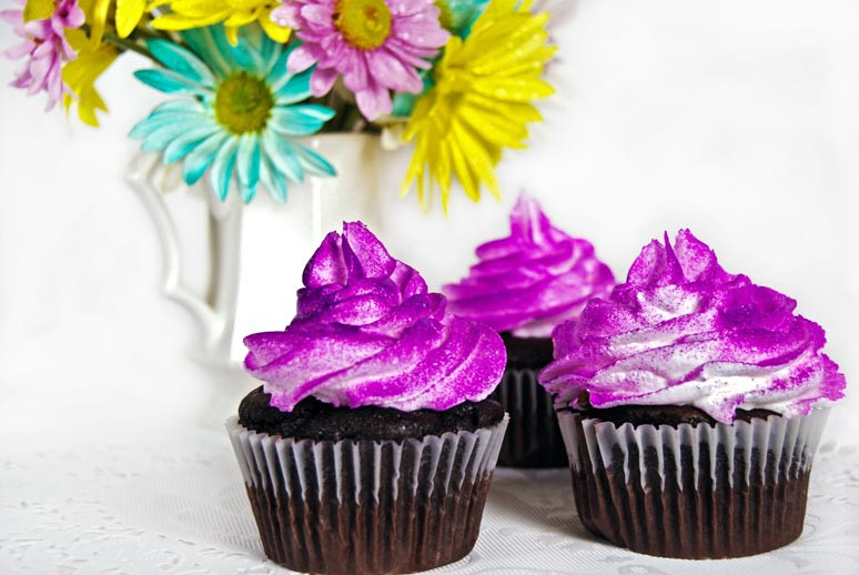 Cupcakes mit Schokolade und Glitzer-Topping vor passender Blumendekoration