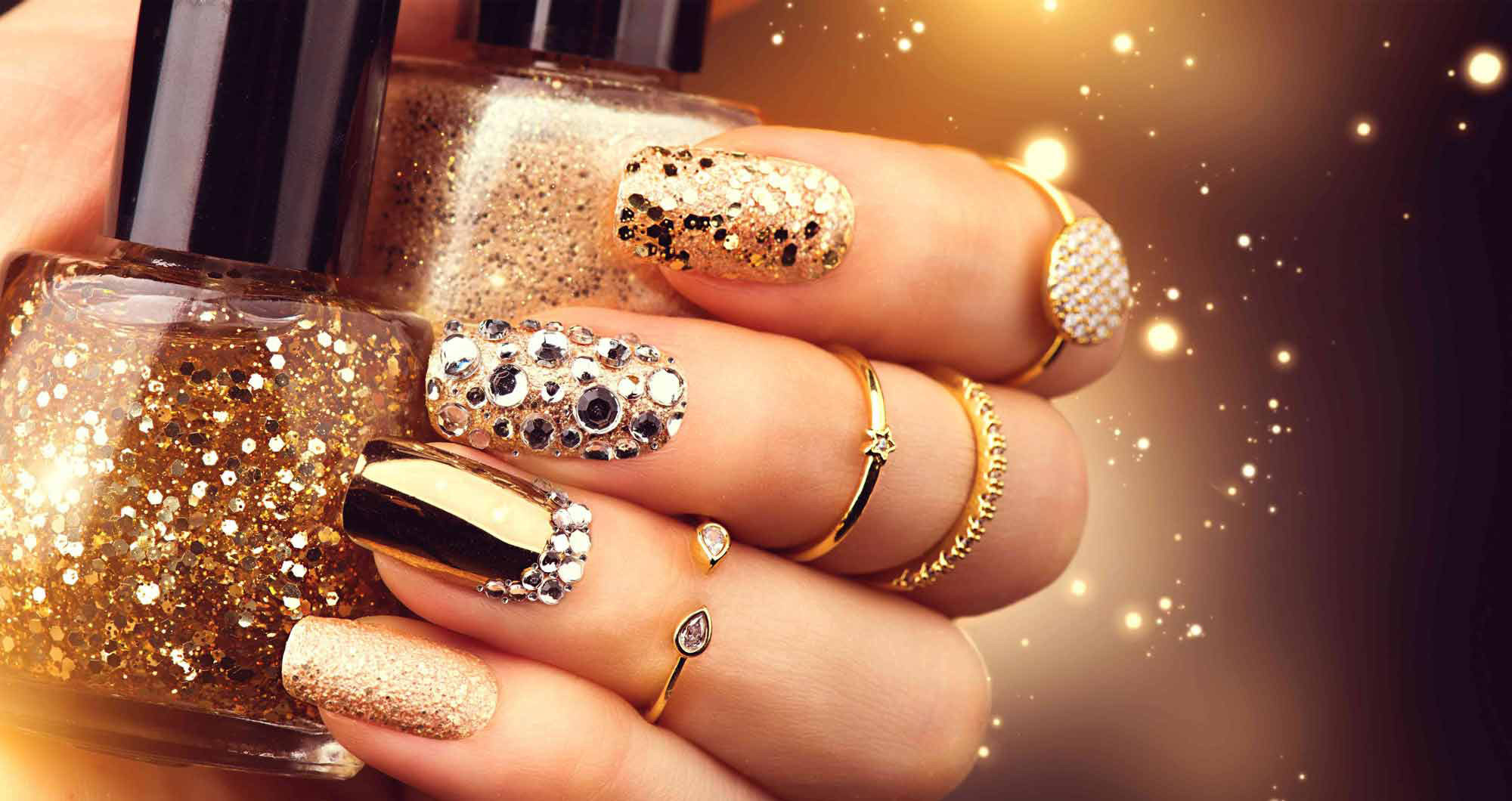 Goldene Maniküre mit Edelsteinen und Glitzern. Flasche Nagellack, trendige Accessoires